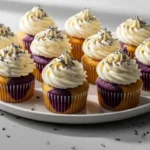 A close-up shot of freshly baked Lavender Honey Cupcakes topped with creamy honey frosting and dried lavender buds.