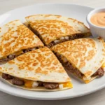 A stack of crispy, golden brown Smash Burger Quesadillas served with a side of dipping sauce.