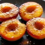 A close-up of golden-brown fried peaches with sugar and cinnamon glaze in a white bowl.
