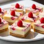 A close-up shot of freshly sliced Lemon Raspberry Swirl Bars showing the vibrant pink fruit pattern and golden crust.