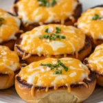 A stack of golden-brown Mini Grilled Cheese Hawaiian Rolls with melted cheese oozing from the sides on a rustic serving platter.