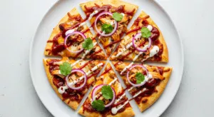 Delicious homemade BBQ Chicken Flatbread, topped with melted cheese, red onions, and fresh cilantro, hot out of the oven.